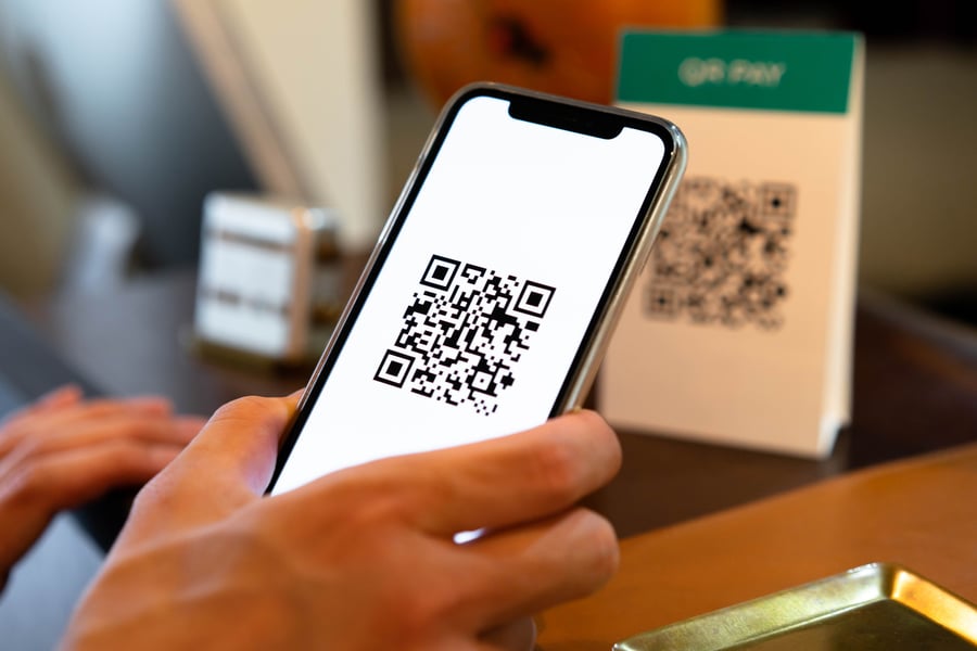 Person holding up a smartphone with a QR code on it - hybrid shopping