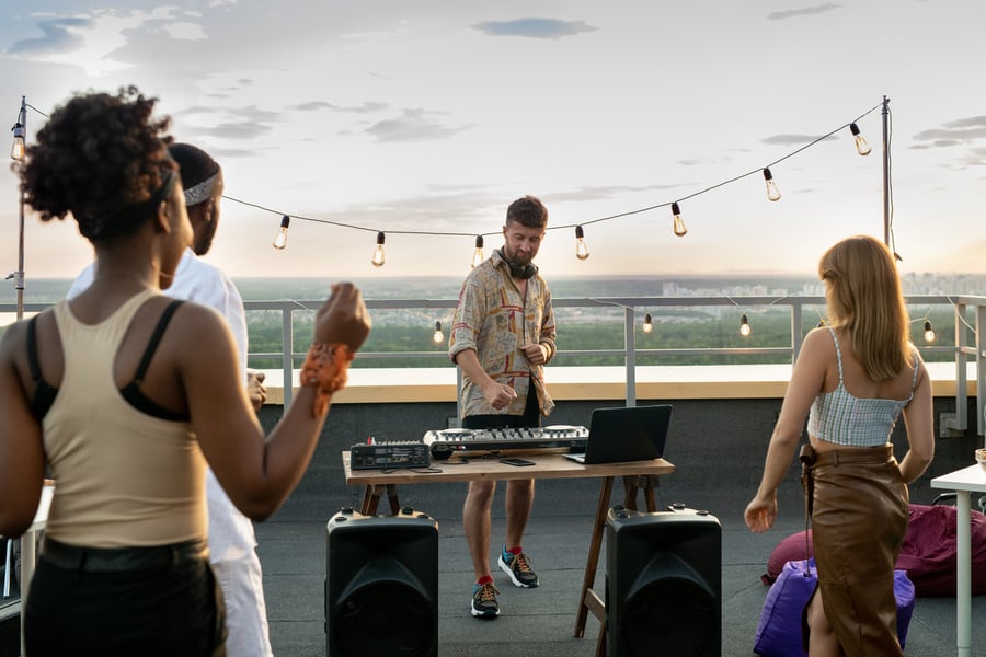 DJ performing at a rooftop event with several people in attendance