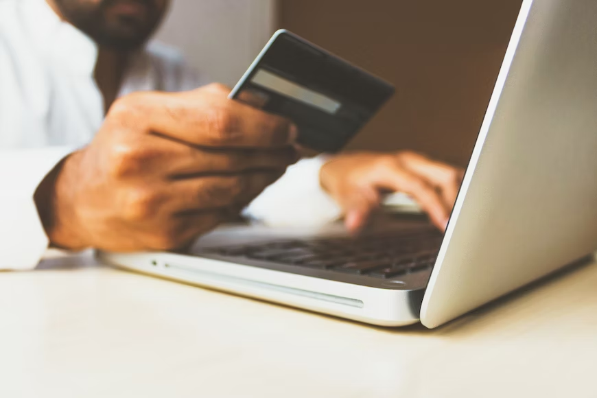 Man making a purchase on his laptop with his credit card as a result of outbound marketing - Shift4Shop