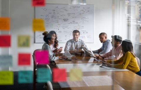 Adults sitting in a room in front of a white board creating a social media strategy.