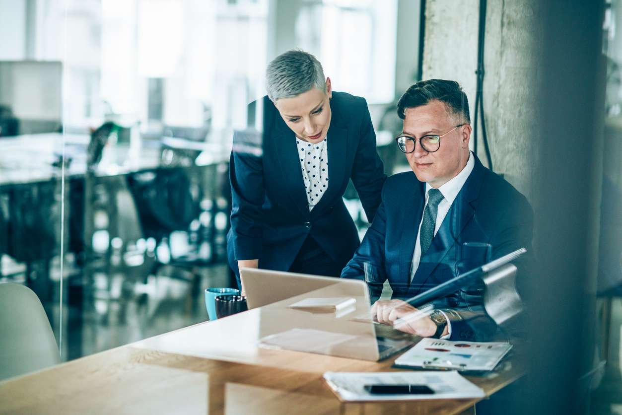 Two enterprise eCommerce business employees performing risk management on a laptop - Shift4Shop