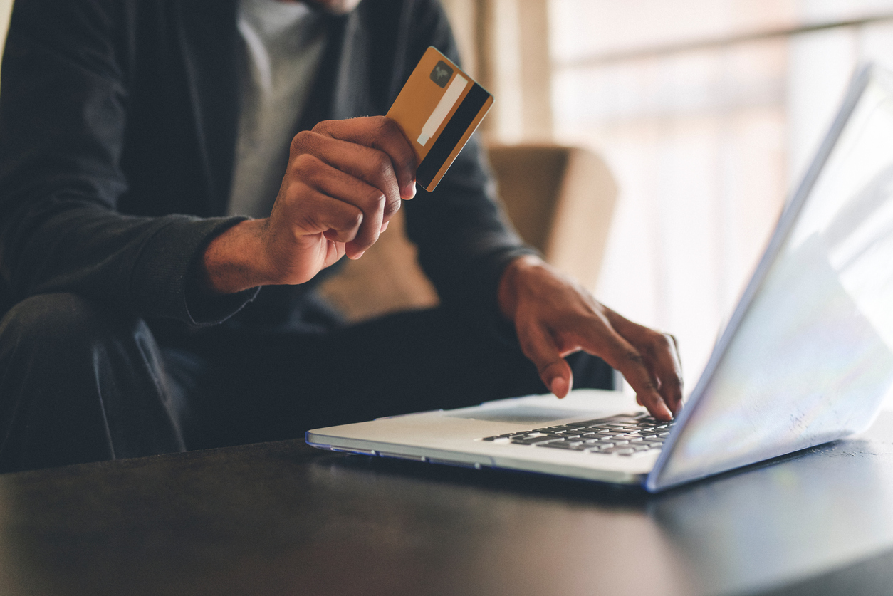 Man holding a credit card about to make a purchase on an online store using a laptop - Shift4Shop