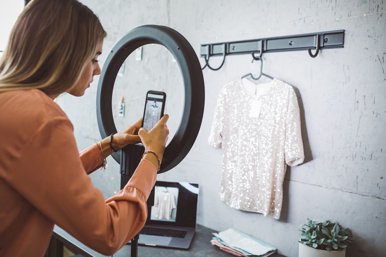 Woman taking an eCommerce image of a t-shirt with her phone for her online store
