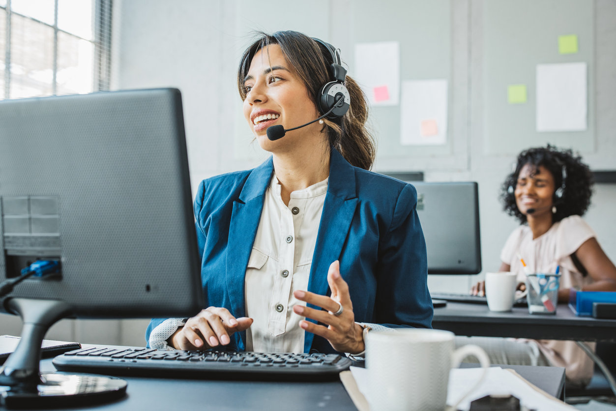 Female customer service agent helping a customer on the phone at her computer - Shift4Shop